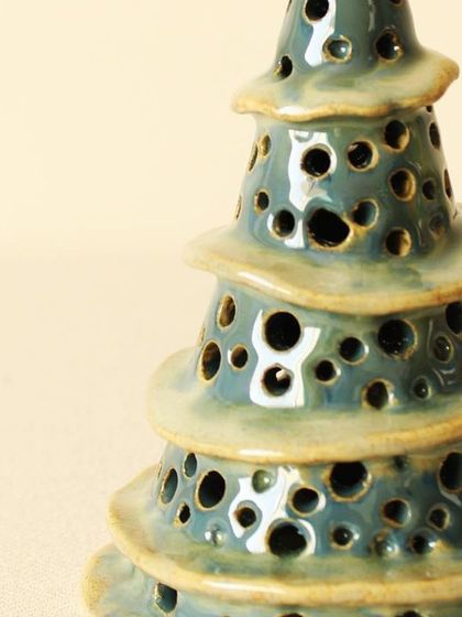 A close-up of the hand-perforated details and the rich, glossy glaze of the Winter Wonderland luminary. Each hole is carefully made when the clay is soft.
