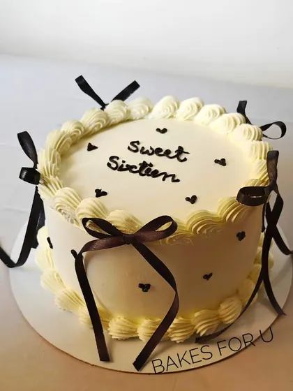"Sweet Sixteen." A classic vintage-style cake with delicate piping and brown ribbon bows, perfect for celebrating a 16th birthday.