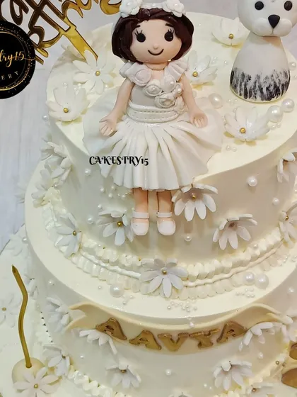 A different angle of the two-tier white princess cake, showcasing the intricate piping work and the charming fondant doll and pet figures that bring this elegant design to life.