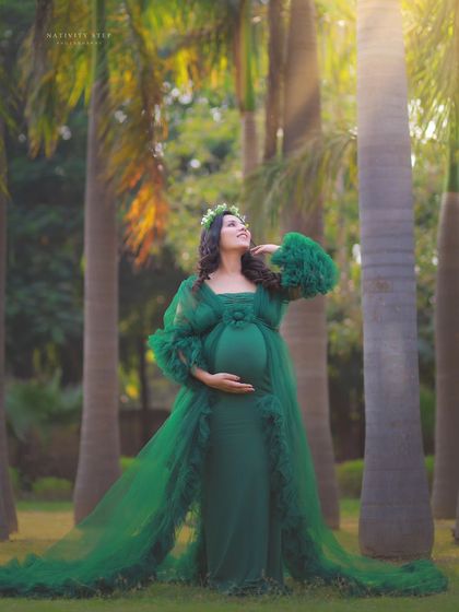 A majestic outdoor portrait in a green gown. The tall palm trees and sun flare create a dramatic and tropical-inspired backdrop.