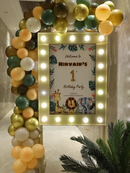 The entrance to Nirvair's jungle party, featuring a welcome sign with a lit-up frame and an organic balloon garland in theme colors.