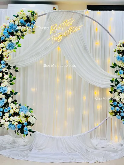 This Roka setup showcases a modern and elegant design using a circular ring frame. The combination of white and powder blue florals against a softly lit white drape creates a dreamy and sophisticated atmosphere for your engagement or anniversary.