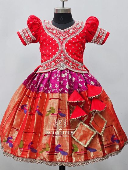 A grand red and magenta lehenga with a Paithani-style border featuring bird motifs. The blouse has intricate silver embroidery.