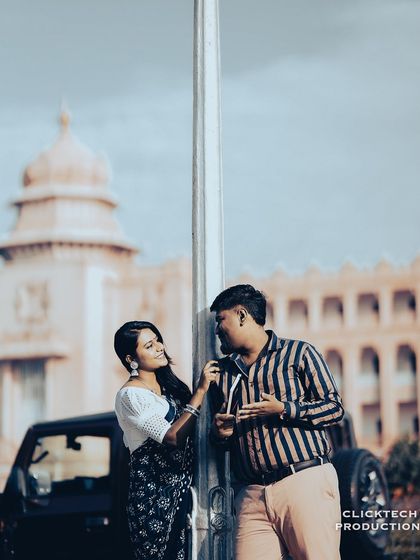 A couple shares a moment by a lamppost, with the iconic Vidhana Soudha in the background, blending romance with Bangalore's heritage.