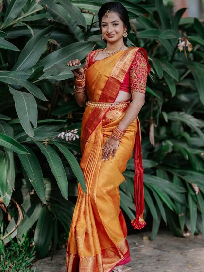 A full-length shot against a natural backdrop, the vibrant saree colour popping beautifully.