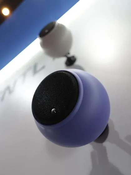 A close-up of the Gallo Acoustics spherical speakers mounted on a wall at the Smart Home Expo. This highlights their compact, modern design and the variety of custom colors available, like this vibrant purple, to match any interior palette.
