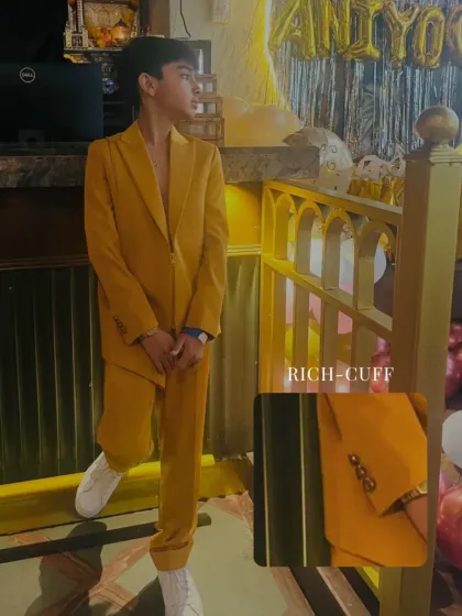 A detail shot of the mustard suit, highlighting the rich color and the fine tailoring of the cuff. It’s a look that exudes confidence and youthful charm.