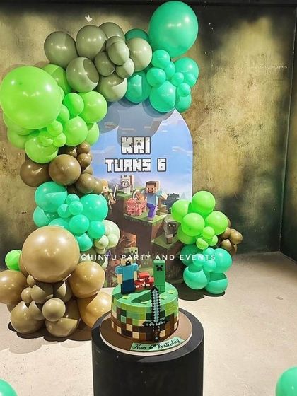 A Minecraft themed 6th birthday party. The decoration uses green and brown balloons to mimic the game's blocky aesthetic, with a themed cake and backdrop.