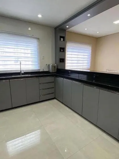 An L-shaped kitchen with matte grey cabinets and a striking black granite countertop that extends into a breakfast bar. The design is simple, functional, and perfect for everyday use.