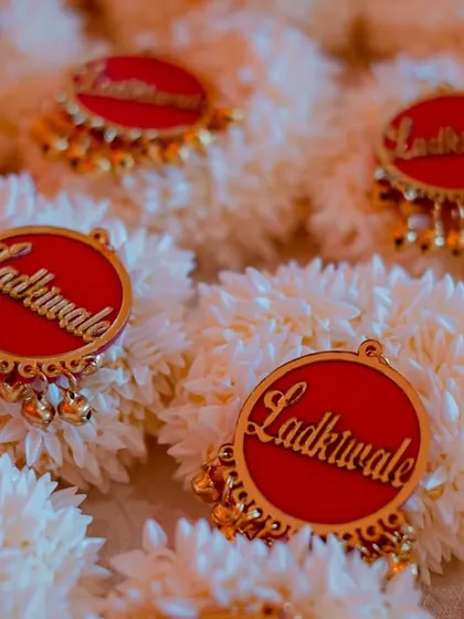 Custom "Ladkiwale" brooches on floral bracelets for the bride's side. These personalized details make family and friends feel special and an integral part of the celebration.