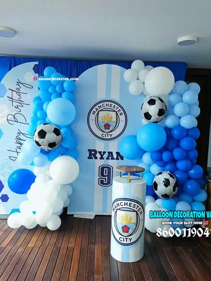 A Manchester City football club theme for Ryan's 9th birthday. The setup features the team's logo on the backdrop and cake plinth, with blue and white balloon decor.
