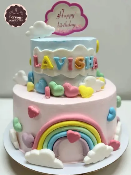 A colourful rainbow theme cake with hearts and clouds. This two-tier cake is perfect for a cheerful and bright birthday celebration, customized with the birthday girl's name.