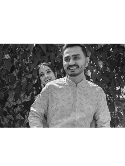 A playful and candid black and white portrait. The bride peeking from behind the groom adds a touch of fun and spontaneity to this lovely shot.