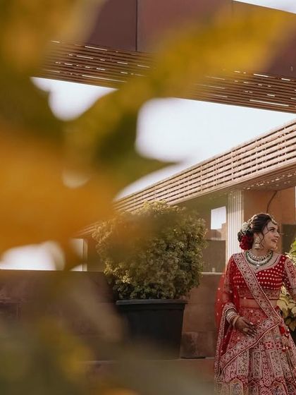 A beautifully framed shot of the couple holding hands on a terrace, with blurred foliage creating a natural frame.