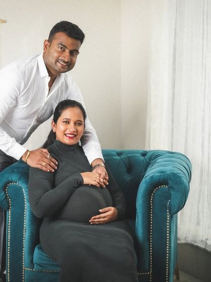 A modern and chic studio maternity session. The elegant black dress and the stylish armchair create a sophisticated setting for this lovely couple's portrait.