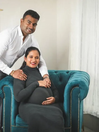 A modern and chic studio maternity session. The elegant black dress and the stylish armchair create a sophisticated setting for this lovely couple's portrait.