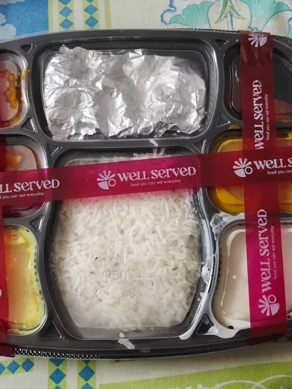 This is how your meal arrives, sealed for freshness with my special "Well Served" ribbon. I make sure everything is packed neatly so you get a perfect thali experience, every time.