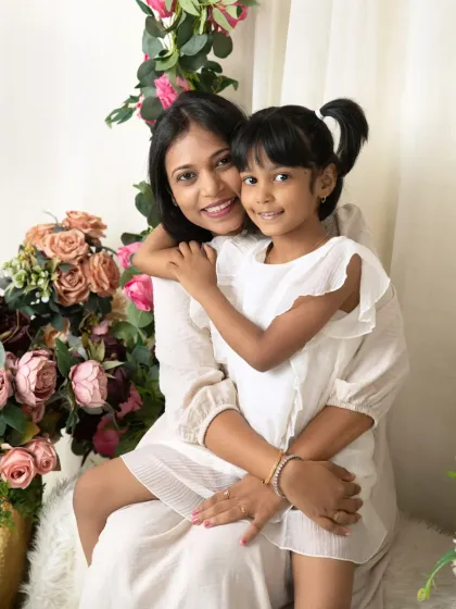 A loving mother-daughter portrait, with the daughter hugging her mom from the side, both radiating happiness.