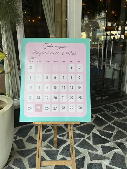 A close-up of the "Take a guess" due date calendar, a fun and interactive element for baby shower guests.