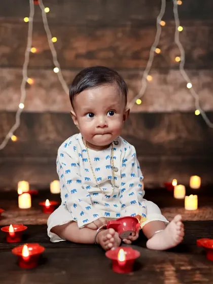Mr. Cute indeed! This baby boy looks so sweet surrounded by diyas, a perfect setup for a Diwali-themed or festive photoshoot.