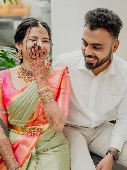 A candid, joyful moment between a couple. The bride's simple yet elegant embroidered pink blouse pairs perfectly with her multi-toned pastel saree.