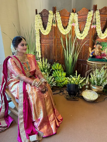 A candid shot of a bride during her wedding rituals, looking serene in a pink and gold saree.