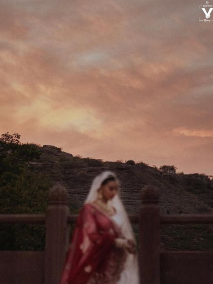 A dreamy, out-of-focus portrait of the bride against a magical sunset sky. The soft blur and beautiful colors create a painterly and romantic image.
