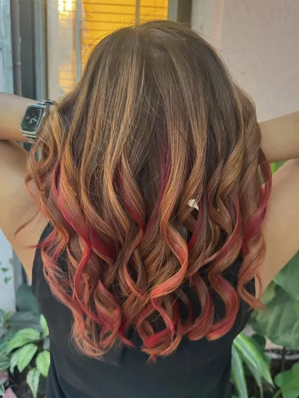 Flaming with style. This look features a mix of red and copper tones on a brown base, all achieved without bleach for a warm, fiery effect.