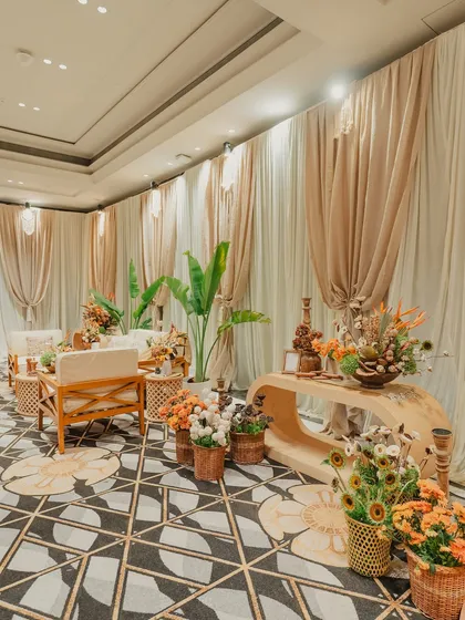 Who said carnivals have to be loud? We designed this elegant lounge area with soft cream tones, natural wood furniture, and lush green plants for a more refined take on a daytime celebration.