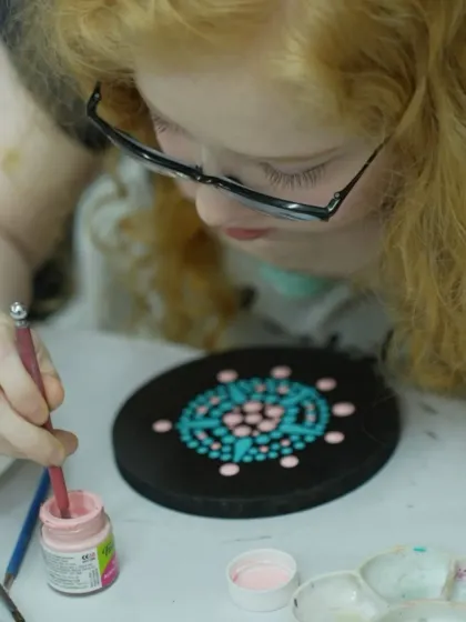 A participant works on her dot mandala, carefully placing each dot to create a symmetrical pattern.