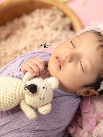 A close-up of a newborn cuddling a small teddy bear. The soft textures and gentle expression make this an incredibly sweet and tender portrait.