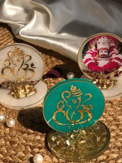 I can customize these resin stands with different idols and colors. This image shows a few variations, including a teal Ganesha, a white Ganesha, and one featuring a photo of a spiritual figure.