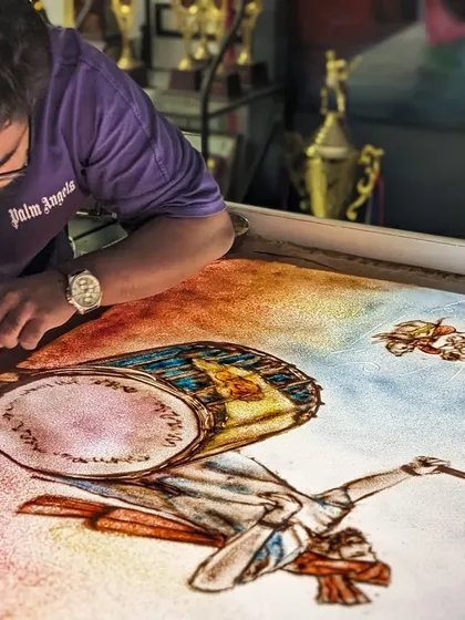 A dynamic scene from a sand art story, showing a person playing a dhol with vibrant colors.