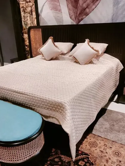 Another look at the dark wood and cane bed, showing the matching ottoman bench with a pop of blue upholstery.