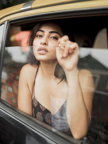 A close-up portrait of Niyati Fatnani through the window of a classic Mumbai taxi, creating an intimate and cinematic feel.