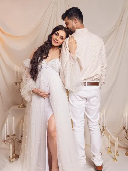 A tender and elegant pose, with the mom-to-be leaning on her partner, surrounded by the soft glow of candles.