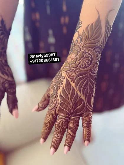 A close-up of a hand filled with intricate leaf and vine motifs. This style is often called "Gulf henna" and is known for its bold, flowing patterns.