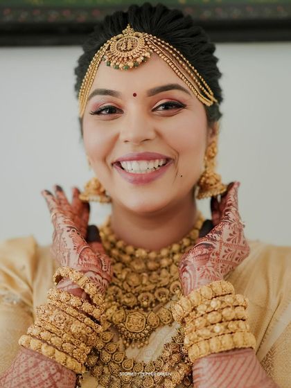 A close-up of the bride's joyful face, her hands framing her smile, showcasing her intricate henna.