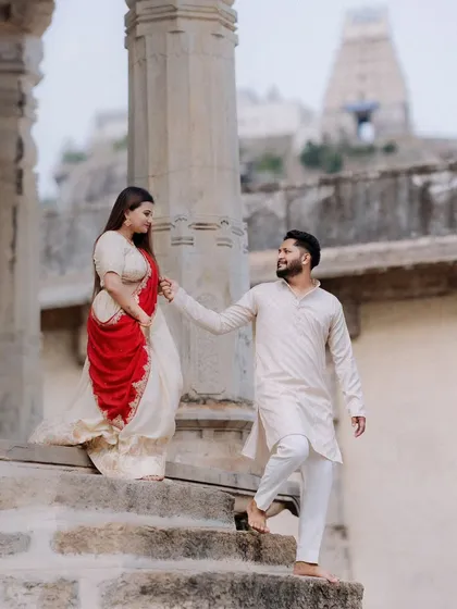 Against the grand, carved stone pillars of a Melukote temple, a couple dressed in traditional attire shares a quiet look. This image showcases a timeless, heritage-themed pre-wedding portrait.