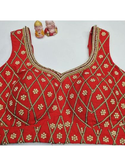 A front view of the red blouse, showing the neat V-neck and the continuous embroidery pattern.