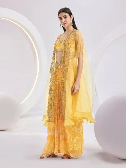 A side view of the RUMI Cape Set, showing the layers of the knotted skirt, blouse, and embellished organza cape.