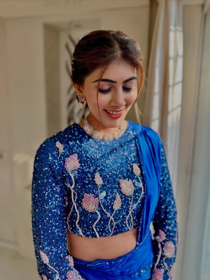 A soft smile that shows her happiness. The makeup is subtle yet impactful, perfect for her sequined blue outfit.