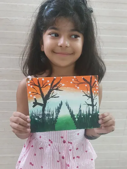 A young girl proudly holds her tricolor-themed painting. This patriotic art project was a creative way to celebrate a national holiday and express love for the country.