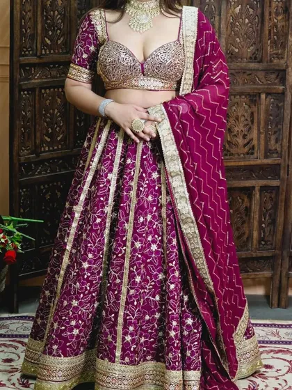 A rich wine-coloured lehenga with vertical gold embroidery, paired with a contrasting gold sequin blouse. This is a very glamorous choice for an evening event.