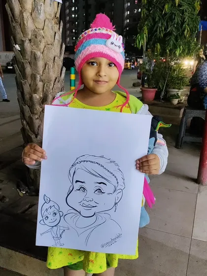 A cute girl in a winter hat holding her caricature, which includes a little drawing of Krishna. I can customize drawings based on requests.