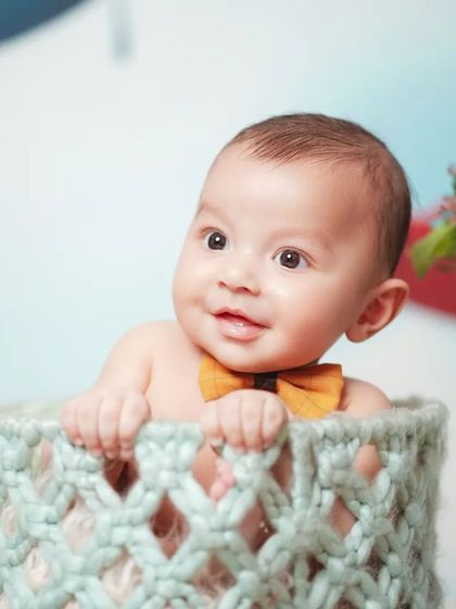 This five-month-old is peeking out of a knitted basket against an airplane-themed backdrop. I offer monthly milestone packages to capture your baby's growth.