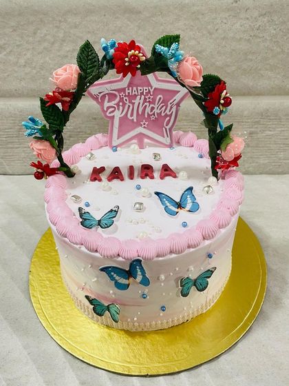 A charming butterfly cake with a floral arch topper, creating a beautiful garden-like effect.