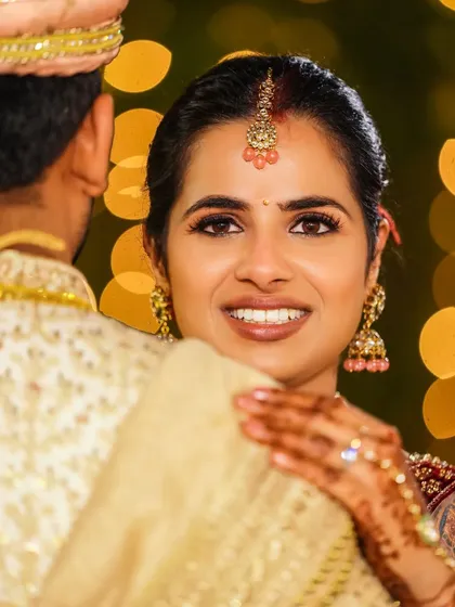 The look of love. This close-up shot captures the bride looking back at her groom, her eyes sparkling with joy against a beautiful bokeh background of evening lights.