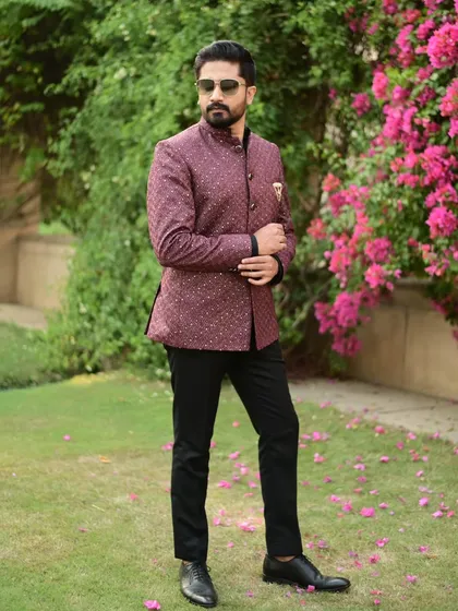 The maroon Jodhpuri jacket, seen in a beautiful garden setting. It's a perfect outfit for a daytime wedding event.