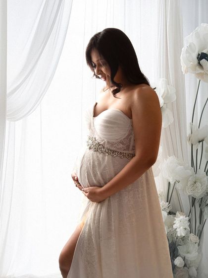 A duplicate of image 39, this classic window-lit portrait captures the serene moment of a mother-to-be connecting with her baby.